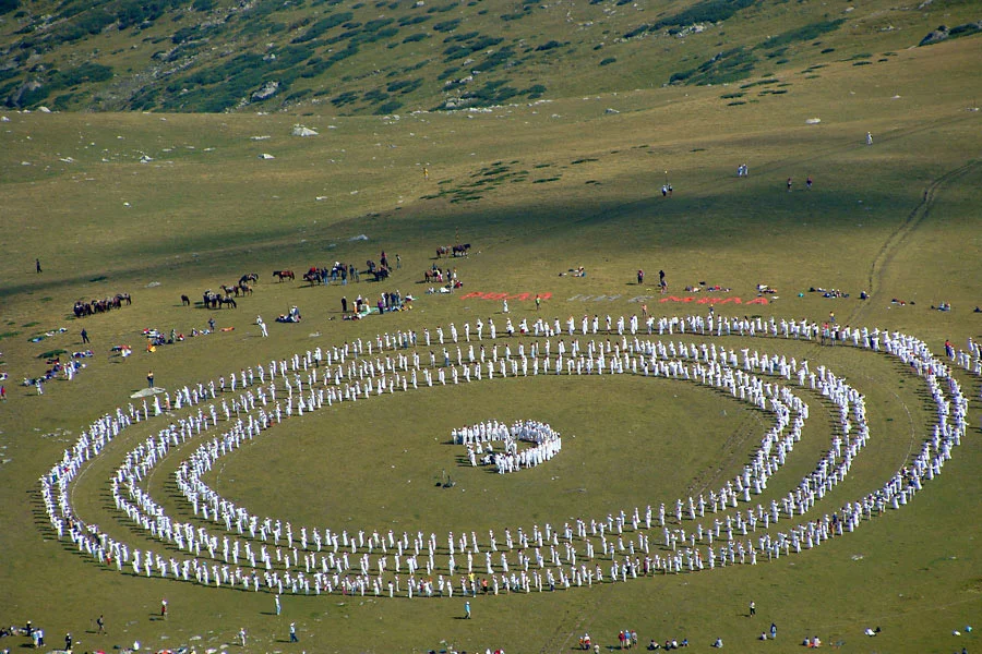 Followers of Peter Deunov dressed in white perform the Paneurhythmy dance in concentric circles on a mountain meadow at the Seven Rila Lakes