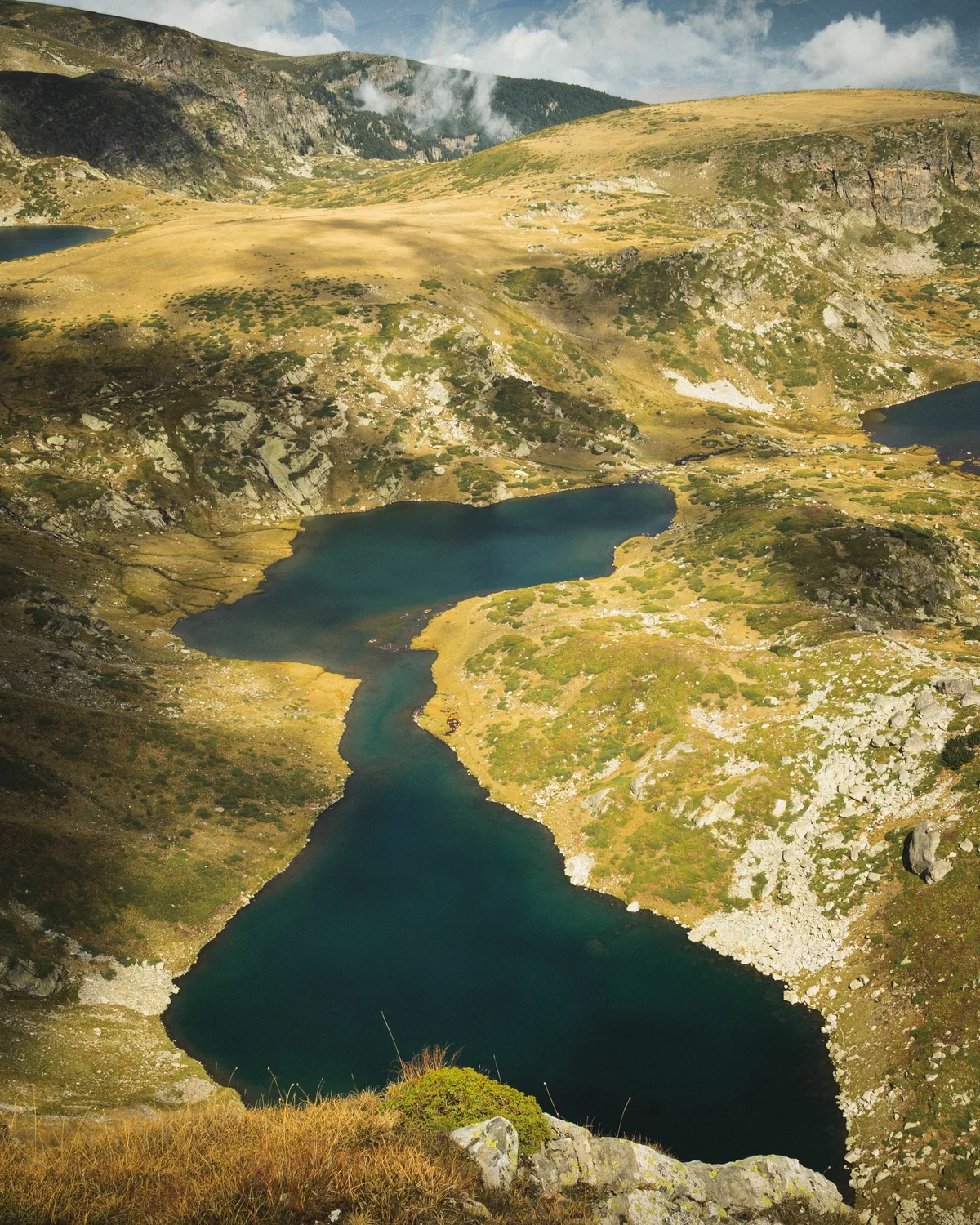 Aerial view of the deep blue Twin Lake (Bliznaka) nestled in the rocky alpine landscape of the Seven Rila Lakes