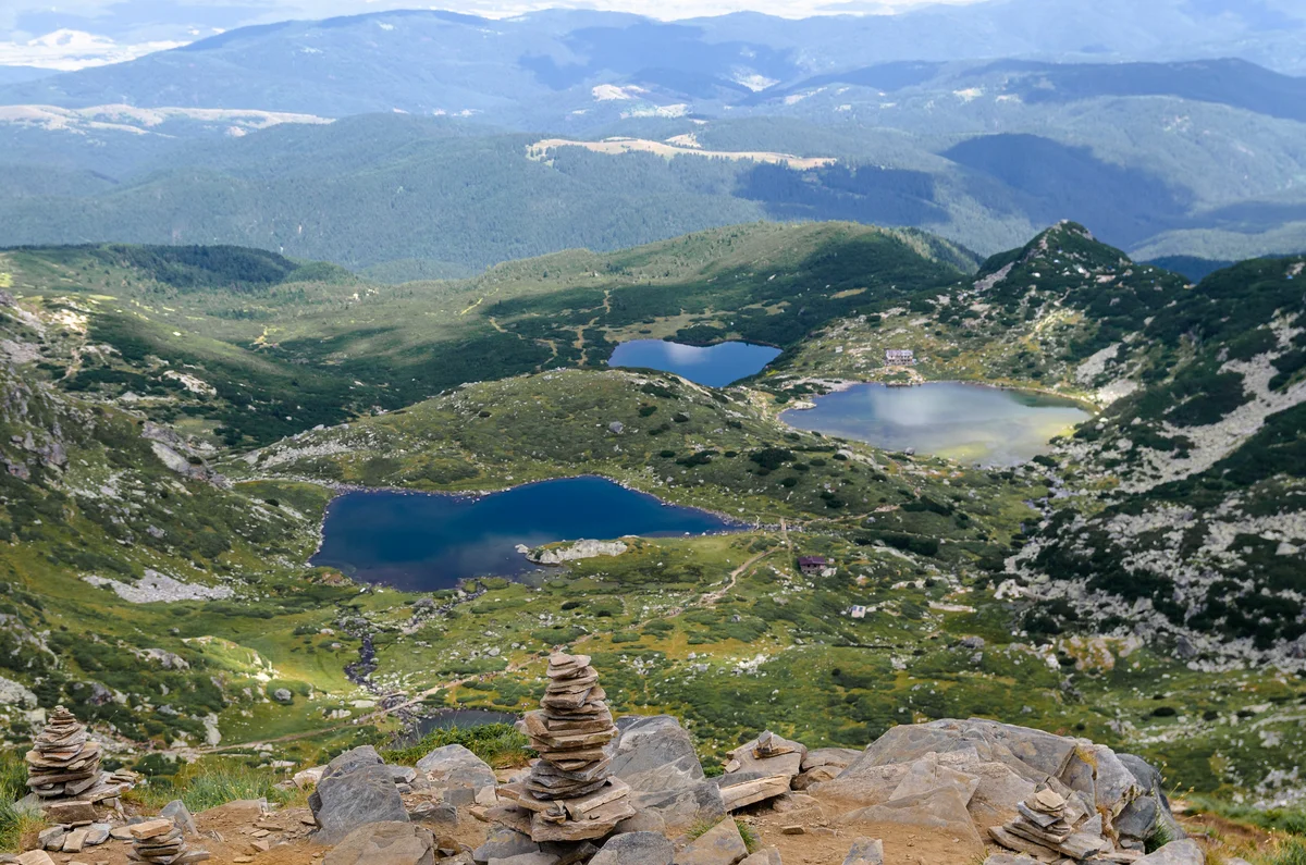 Panoramic view of glacial lakes in the Seven Rila Lakes valley, with rock cairns on a ridge in the foreground